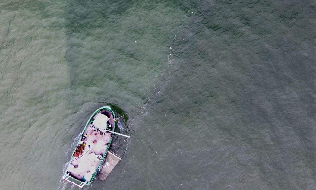 Una nave che pulisce i rifiuti galleggianti accumulati lungo una windrow nel Golfo di Biscaglia